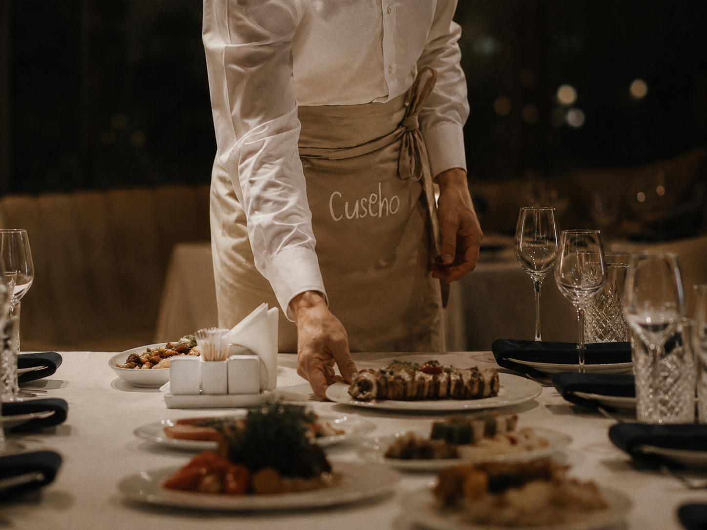 Cuseho server in a branded apron setting a banquet table at a Singapore event