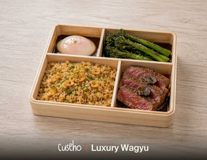 Luxury Wagyu bento in a wooden box with truffle glazed wagyu striploin, garlic fried rice, charred broccolini and a soft onsen egg. Cuseho Asian fusion bento catering, Singapore