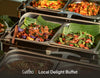 A buffet display of local dishes in stainless steel chafing trays lined with banana leaves, featuring colorful cooked vegetables and proteins. The text 'Cuseho | Local Delight Buffet' is visible at the bottom.